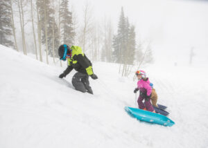 three kids and their sleds in the snow